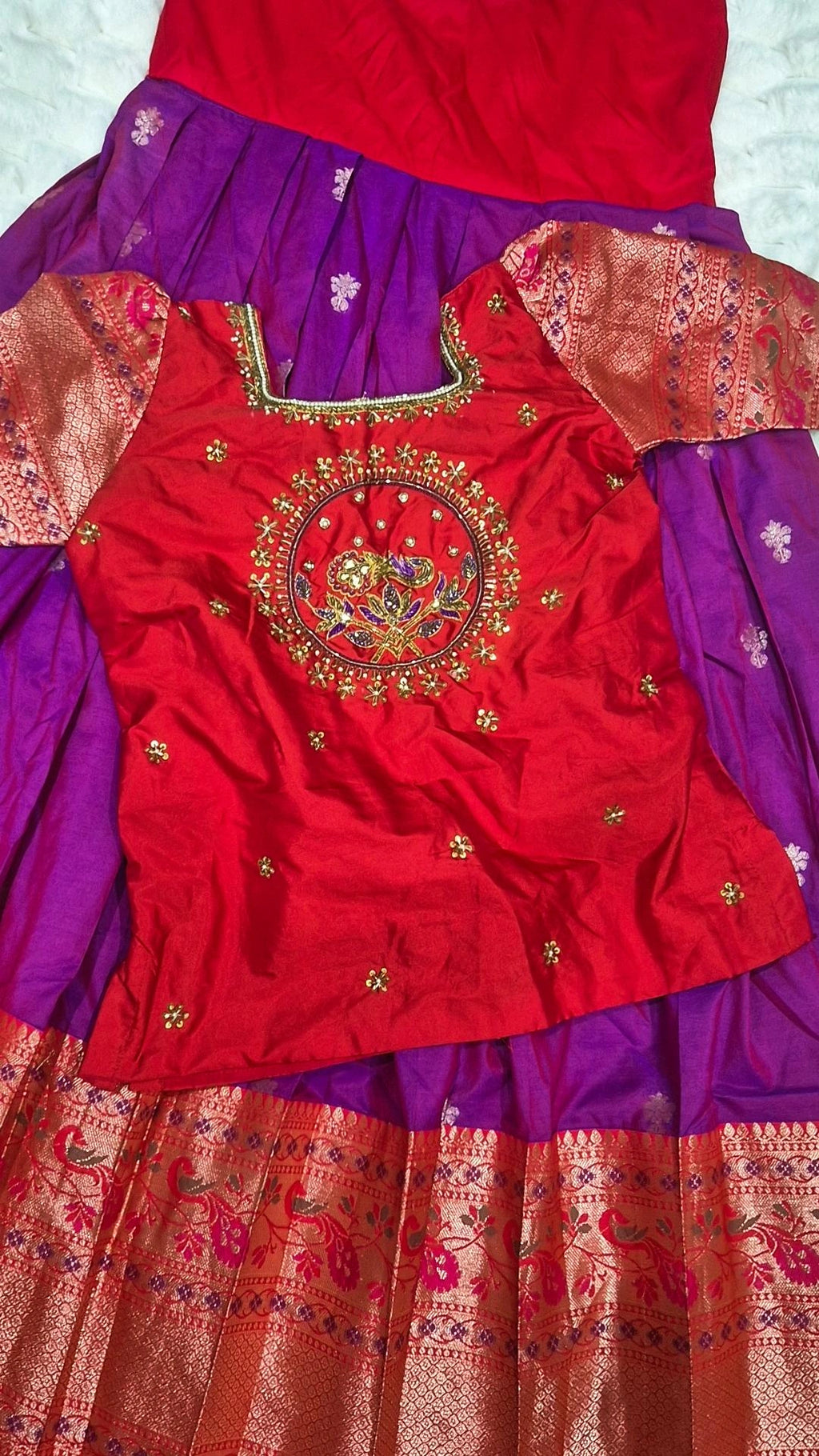 Red embroidered blouse with peacock motif and purple pattu pavada skirt