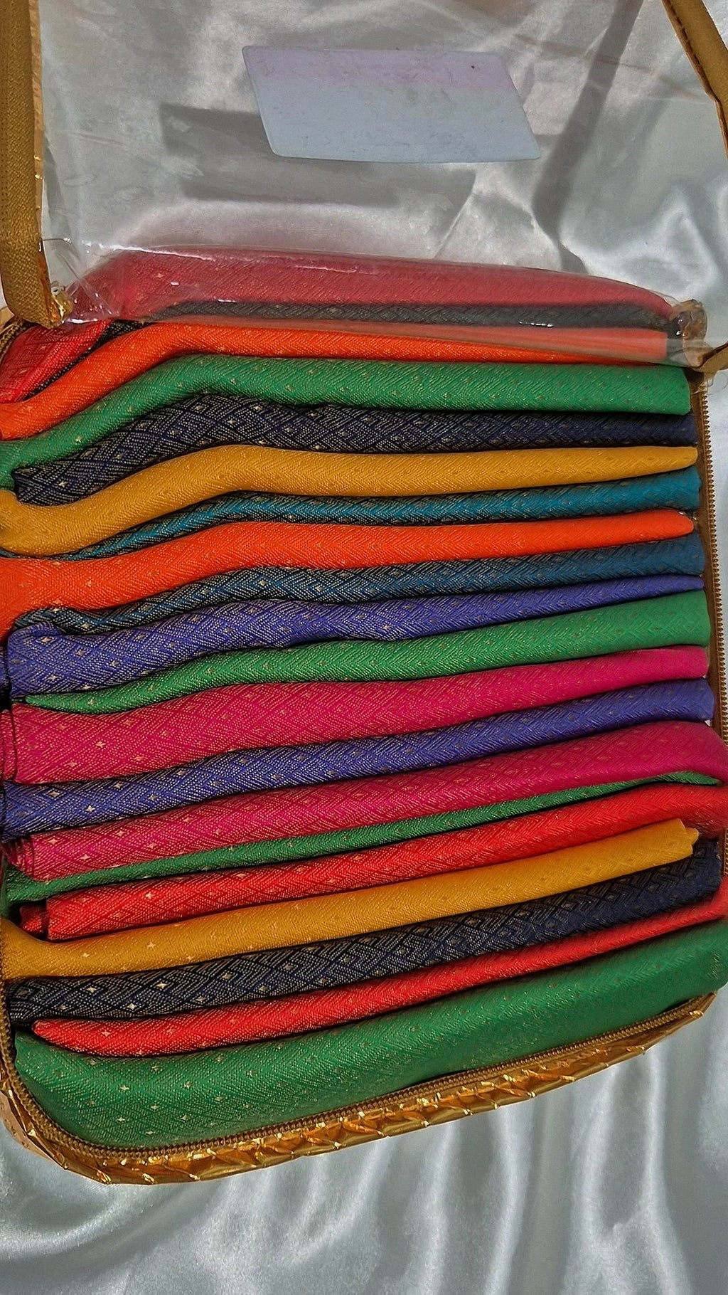 Banarasi silk blouse pieces in multiple colours stacked in a gold-trimmed box