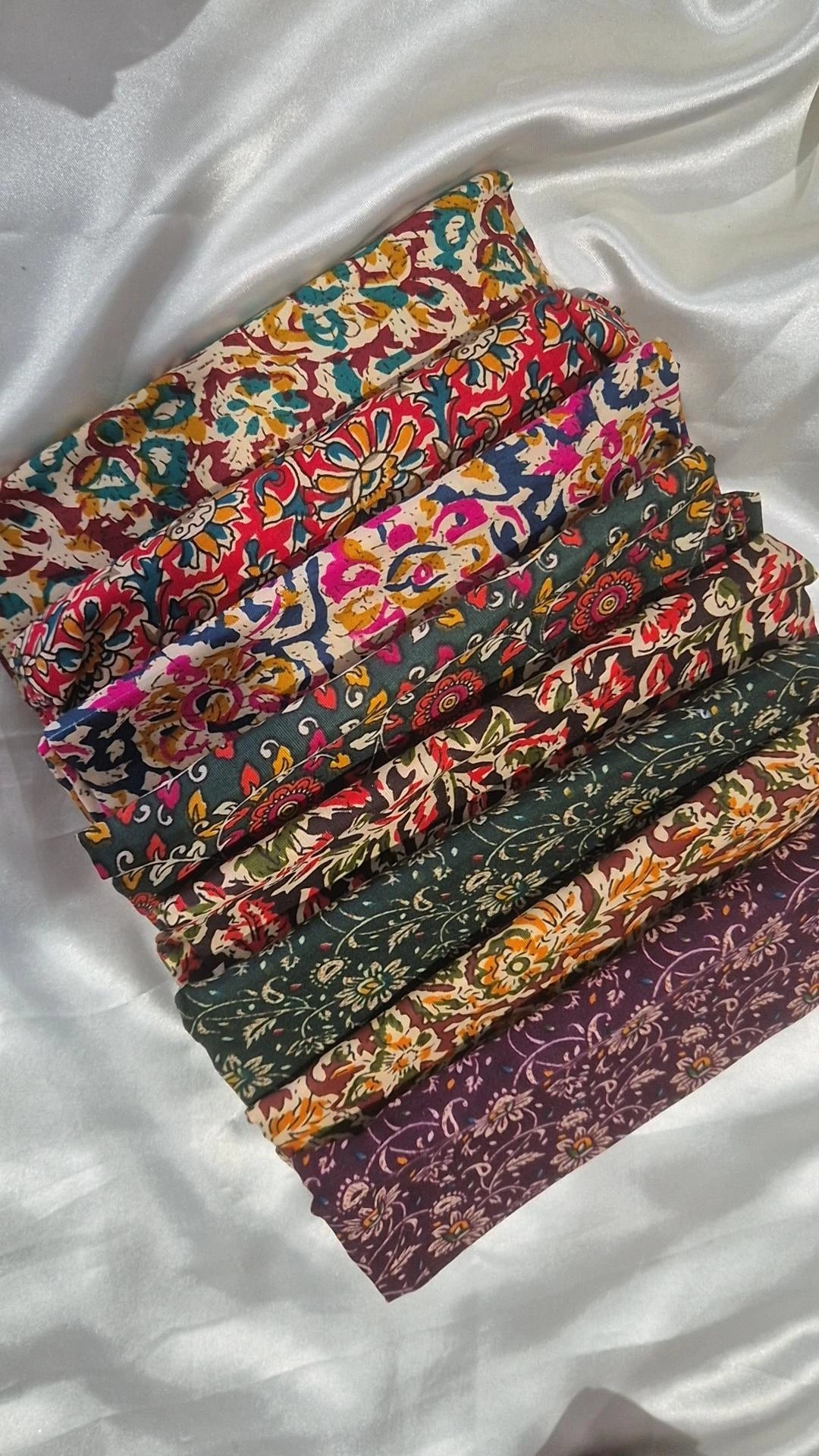 Stack of colourful Indian block print blouse pieces with earthy tones and purple at bottom