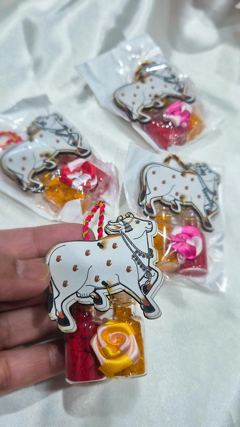 Kamdhenu cow haldi kumkum favor held in hand with packaged pieces behind
