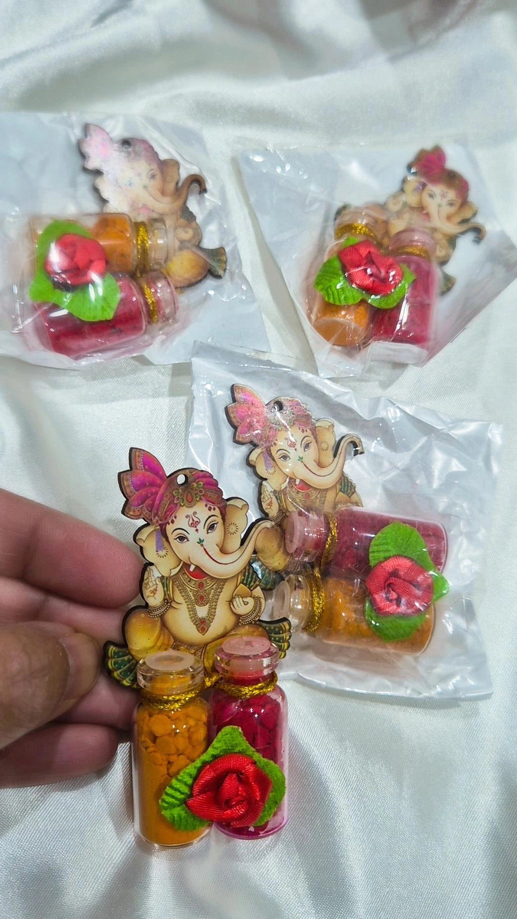 Ganesha haldi kumkum favor held in hand with packaged pieces behind