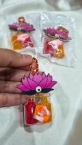 Pink lotus haldi kumkum favor held in hand with packaged pieces behind