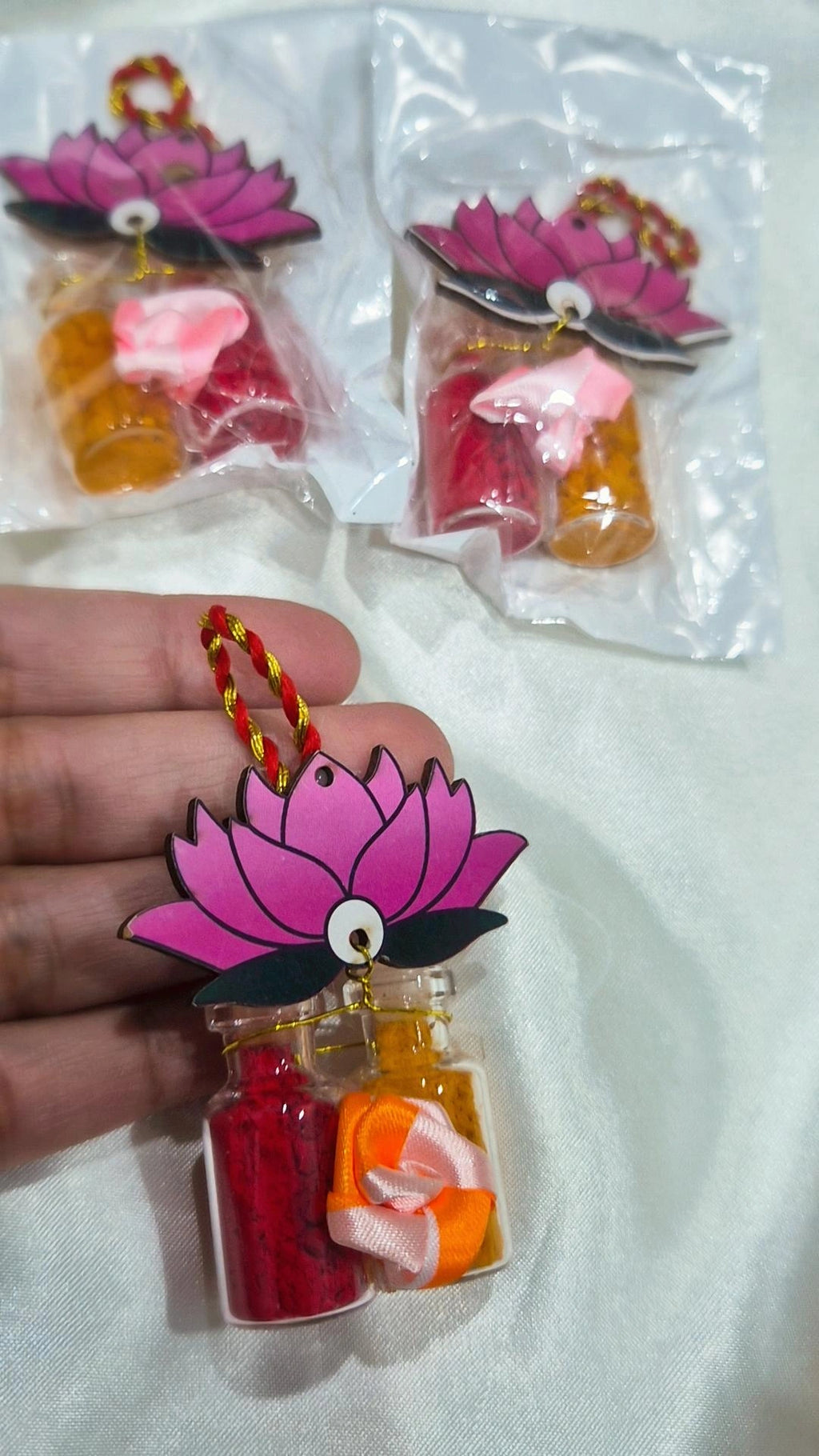 Pink lotus haldi kumkum favors packaged on white fabric