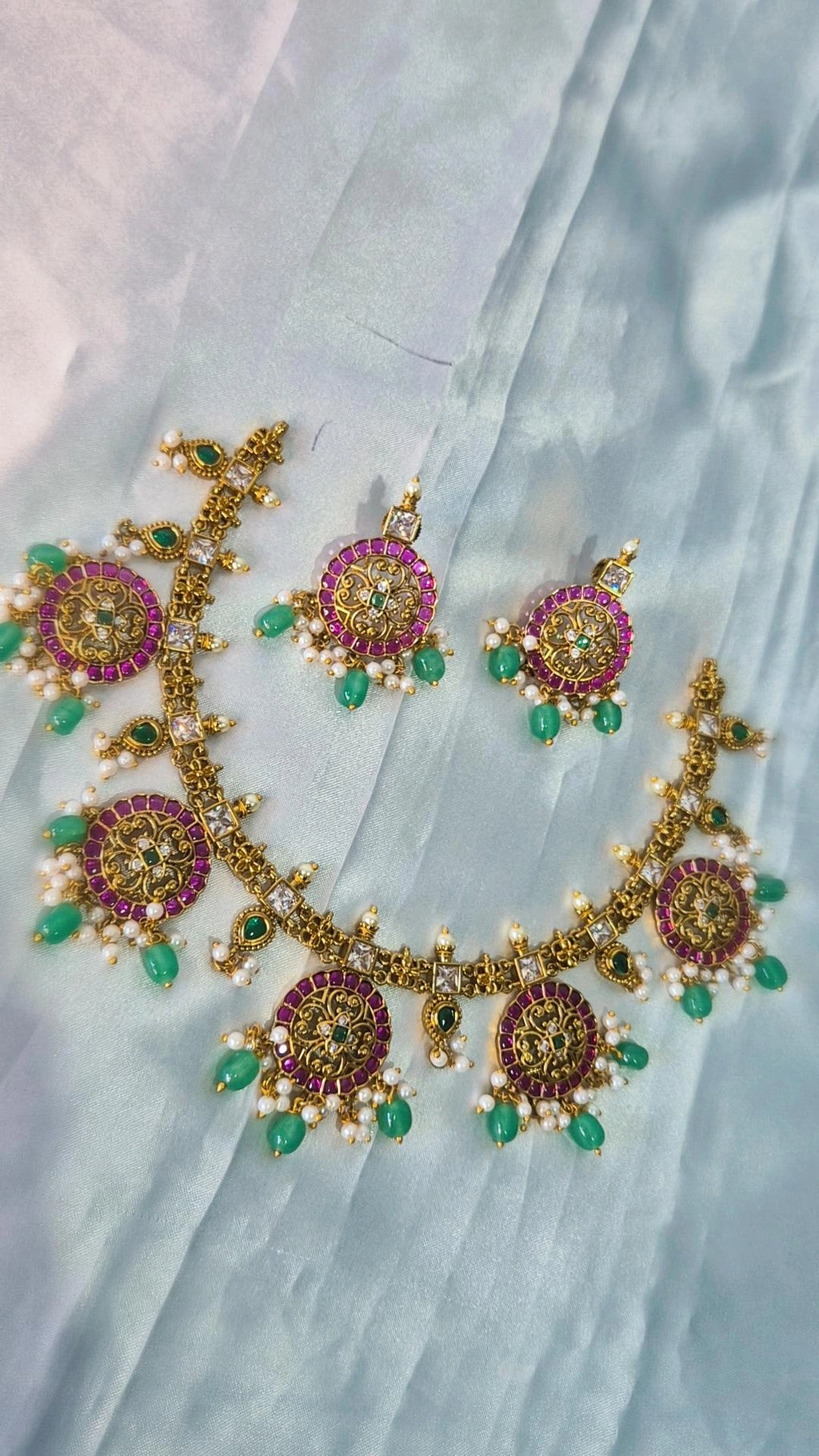 Kemp ruby emerald necklace with matching earrings laid flat on white fabric