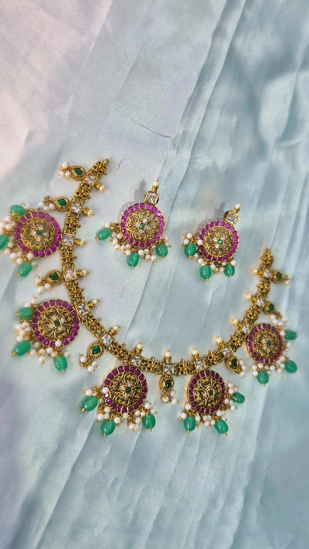 Kemp ruby emerald necklace with matching earrings laid flat on white fabric