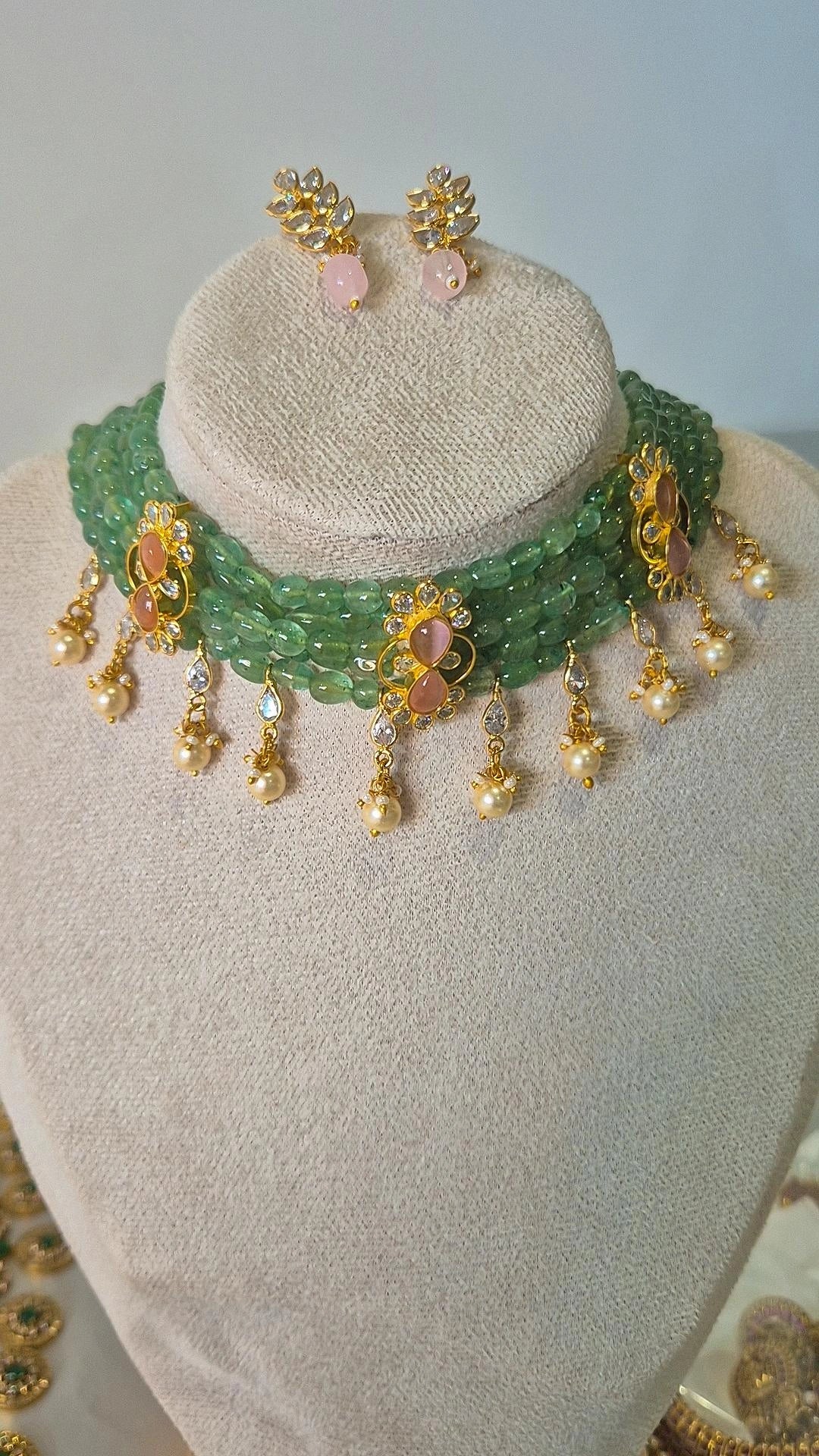 Emerald bead choker necklace with gold floral connectors and pearl drops displayed on jewellery bust