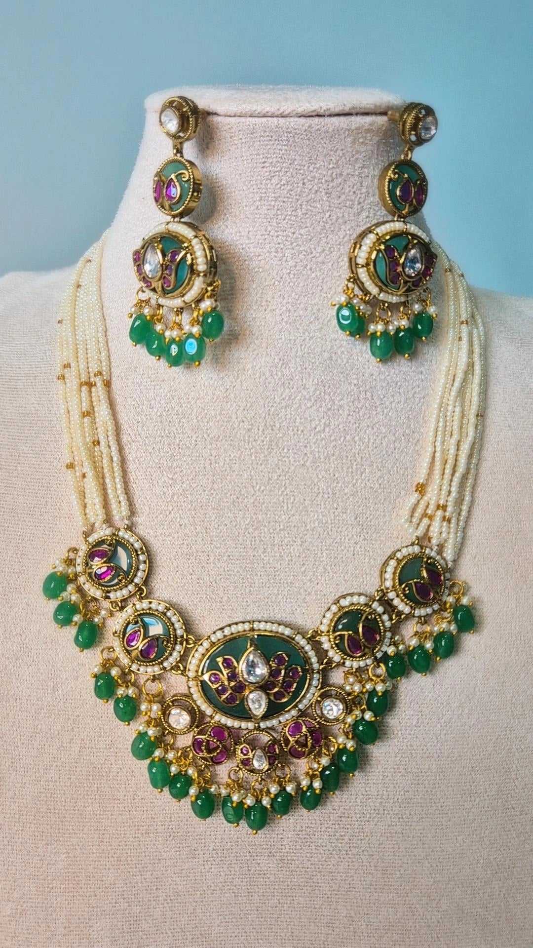 Jadau Kundan emerald green medallion necklace with chandbali earrings displayed on jewellery bust