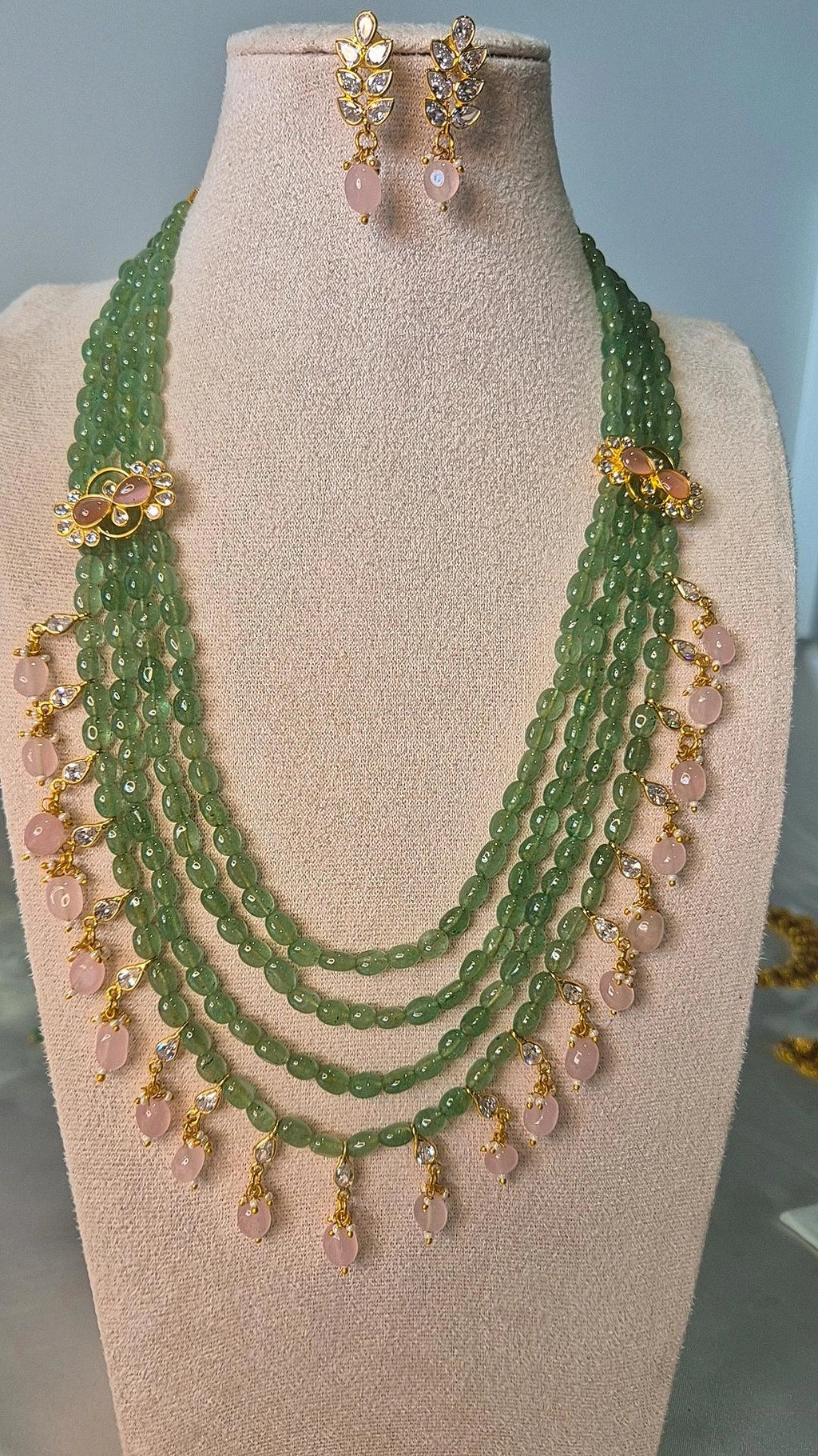 Jadau Kundan multi-strand emerald bead long necklace with rose quartz drops and matching earrings on jewellery bust