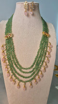 Jadau Kundan multi-strand emerald bead long necklace with rose quartz drops and matching earrings on jewellery bust