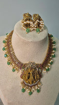 Lakshmi temple jadau choker necklace with ruby chain, pearl drops and emerald beads displayed on jewellery bust with matching jhumka earrings