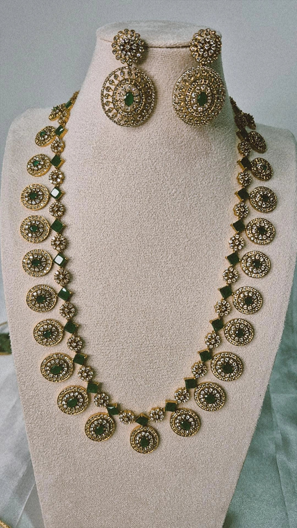 Victorian gold CZ emerald long Bottu Mala necklace set with emerald green links and matching circular drop earrings on jewellery bust