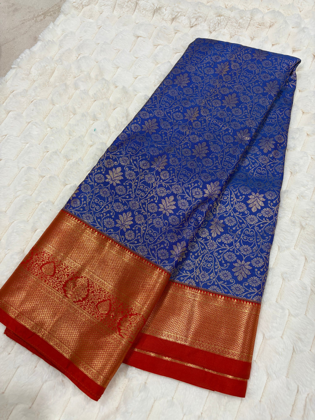 Royal blue Kanjivaram silk saree folded showing all-over silver zari jaal and red gold border