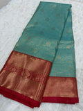 Teal Kanjivaram silk saree folded showing all-over gold zari lotus jaal and deep red border