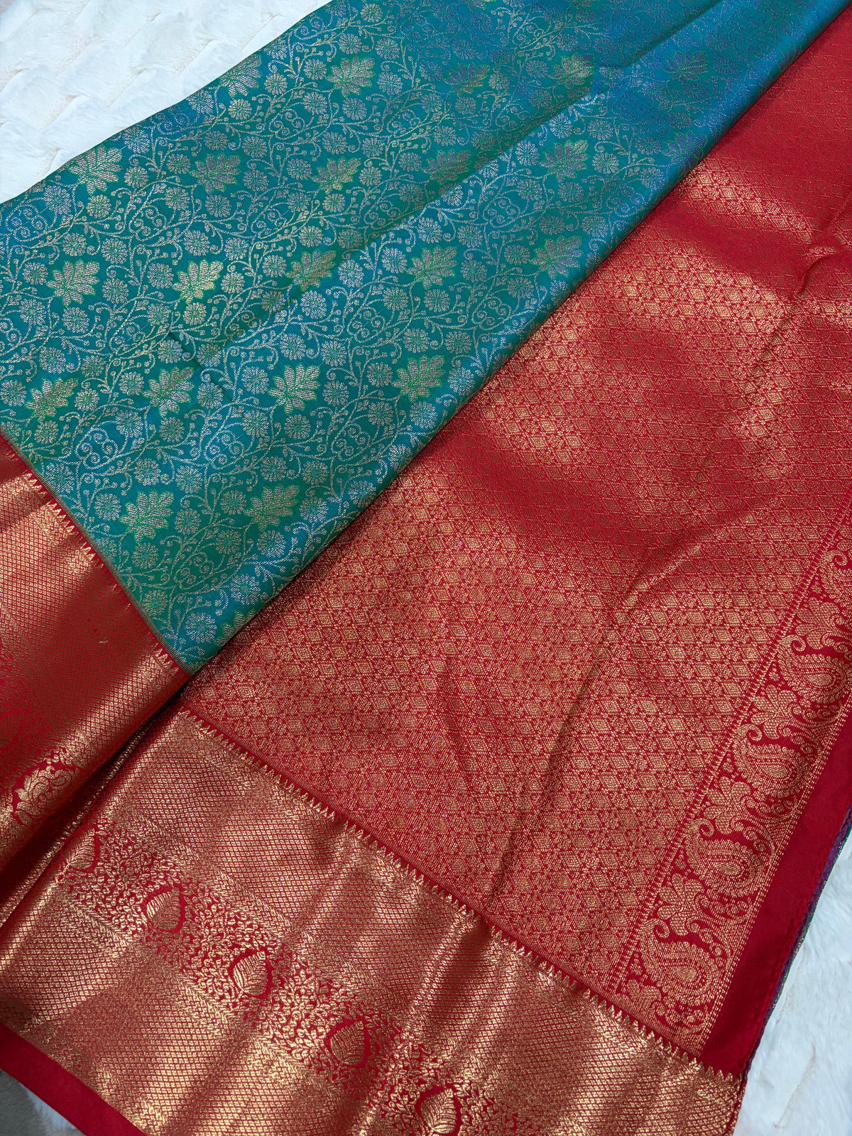 Close up of teal Kanjivaram saree body with gold zari jaal and red pallu with peacock motifs