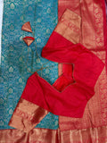 Red boutique stitched blouse with Kanjivaram zari sleeves laid on teal saree with dori ties - back view