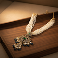 White pearl emerald necklace on wooden tray
