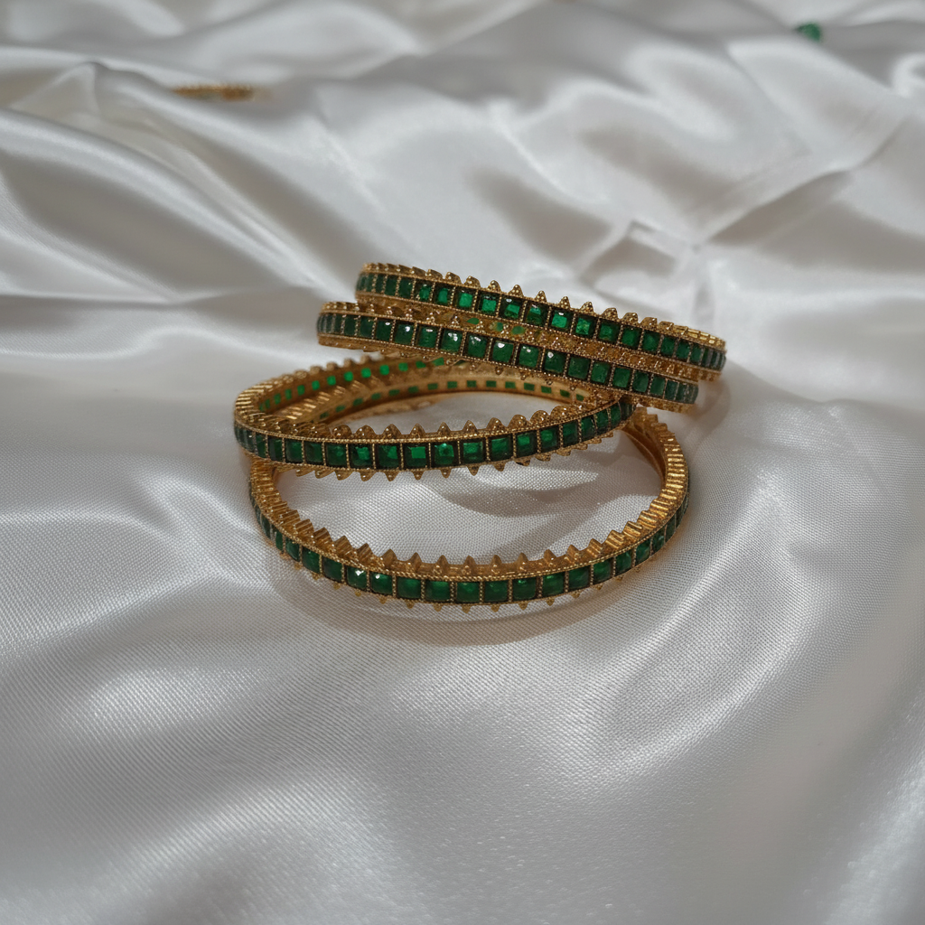 Emerald green stone gold bangles on white satin