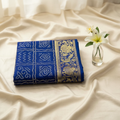 Blue Bandhani Kanjivaram saree on cream background with flower vase