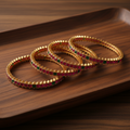 Ruby red and emerald green bangles on wooden tray